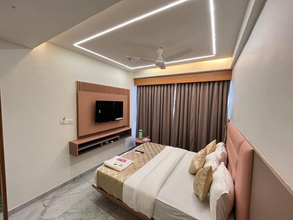 a bedroom with a bed and a flat screen tv at Hotel Melbourne in Gandhinagar