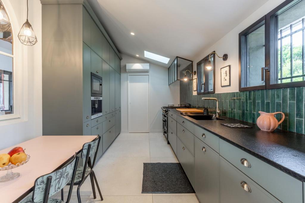 a kitchen with green and white cabinets and a counter at Demeure d'exception vue mer in Andernos-les-Bains