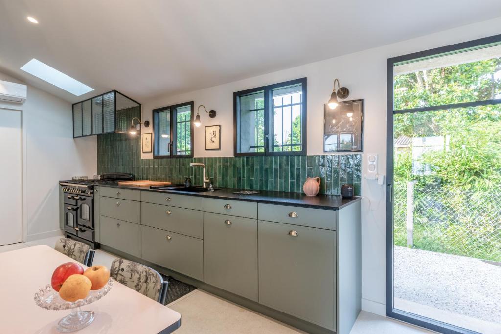 a kitchen with gray cabinets and a table with a bowl of fruit at Demeure d'exception vue mer in Andernos-les-Bains