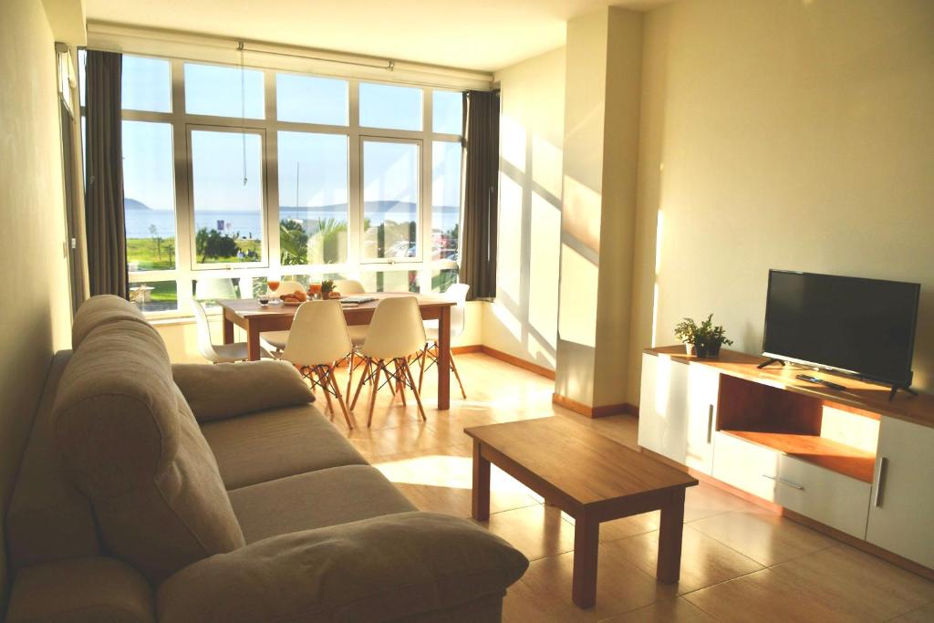 salon z kanapą, telewizorem i stołem w obiekcie Primera Linea de Playa Samil Costa con Garaje Incluido w mieście Vigo