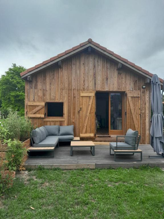 - un bâtiment en bois avec un canapé et des chaises sur une terrasse dans l'établissement Cabane et jardinet, à Magescq