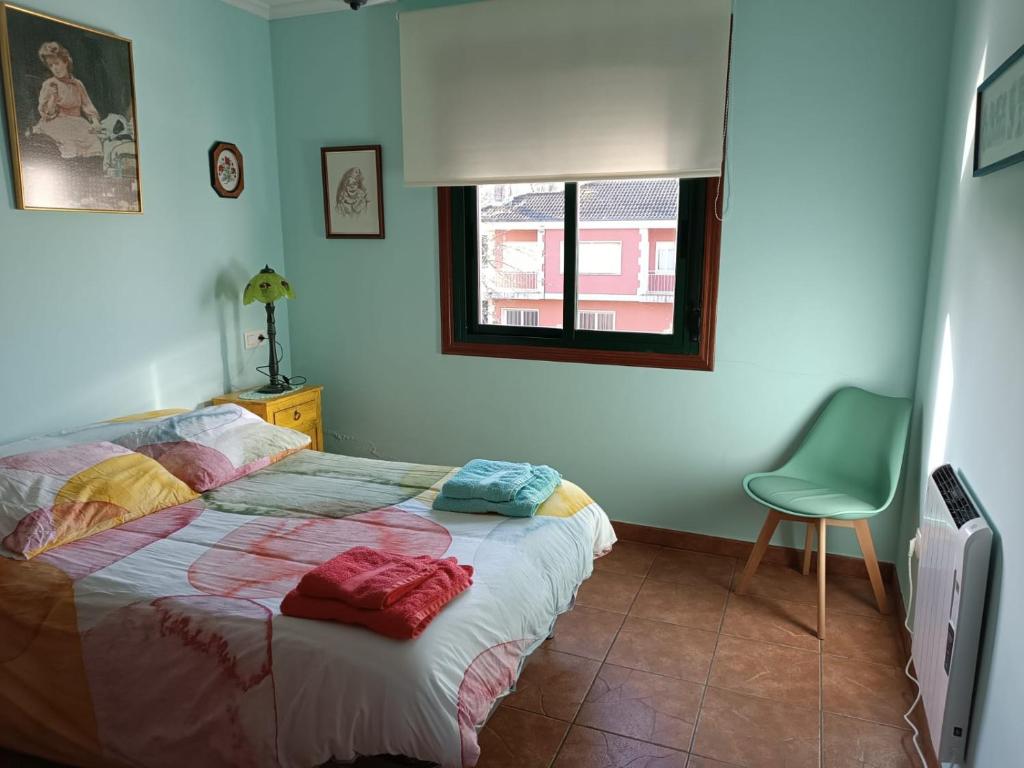 a bedroom with a bed and a green chair at As Lamelas in Cea