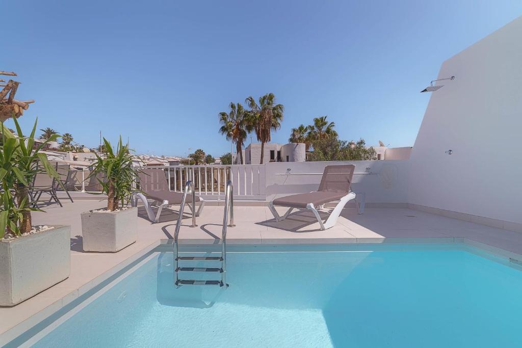 a swimming pool with chaises and chairs on a patio at Villa Nina Lanzarote in Puerto del Carmen