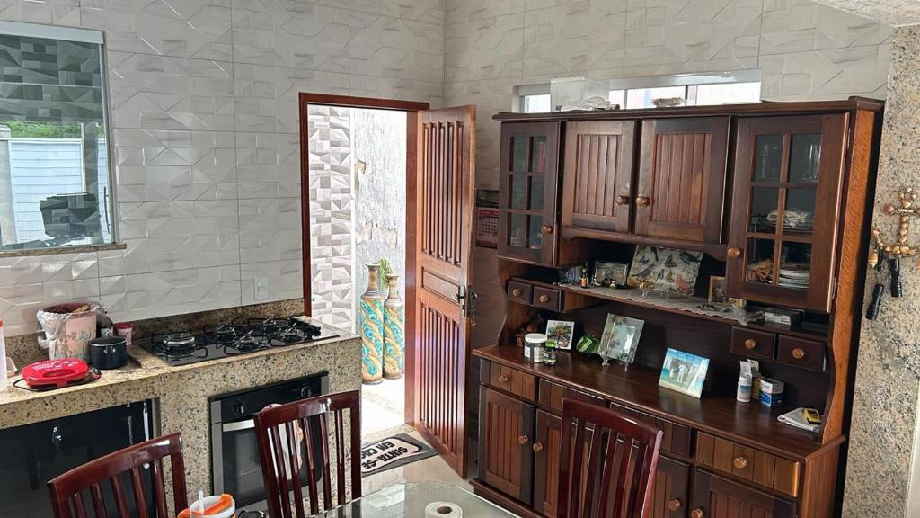 a kitchen with wooden cabinets and a table with chairs at Casa aconchegante in Rio das Ostras