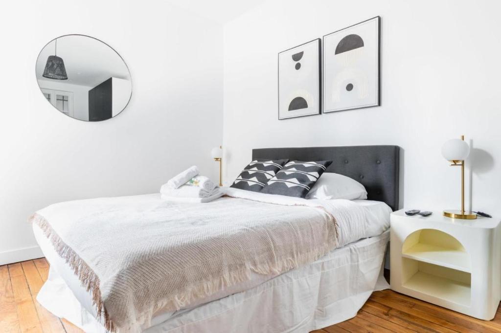 une chambre blanche avec un lit et un miroir dans l'établissement Appartement service Studio au Coeur du 19e - 2P, à Paris