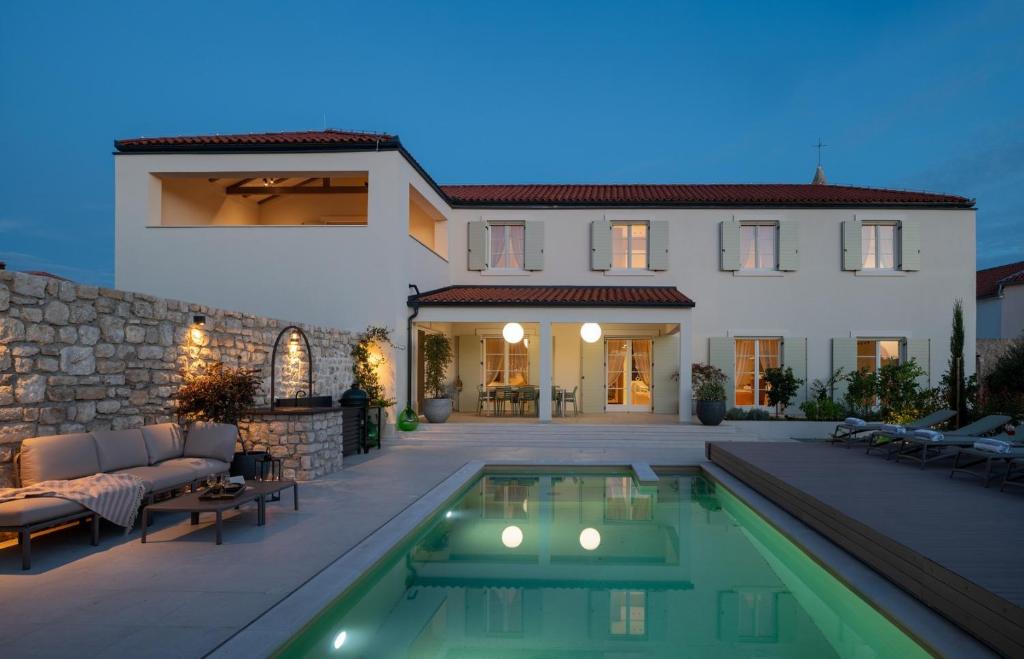 a house with a swimming pool in front of a house at Luxury Villa Marca heated pool 36m2 in Nin
