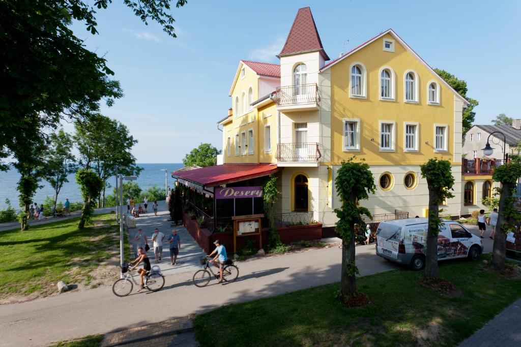 people riding bikes down a street in front of a yellow house at DW California in Rewal