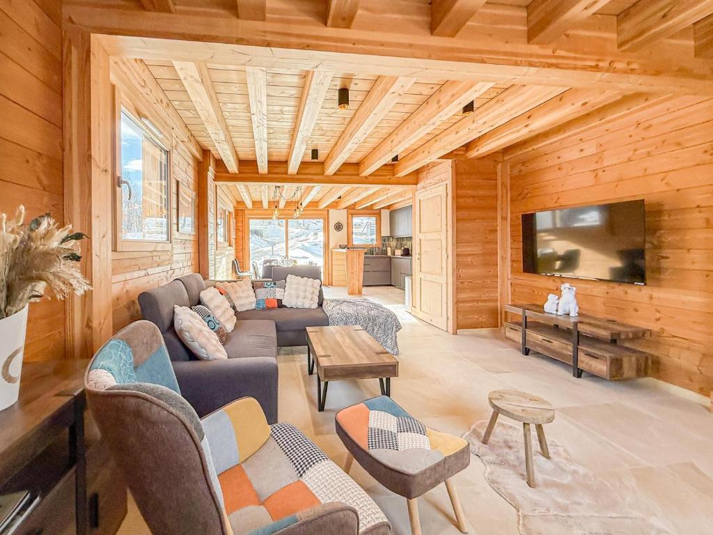 Una sala de estar con un sofá y un televisor. en Chalet neuf le doux glace, en Valloire