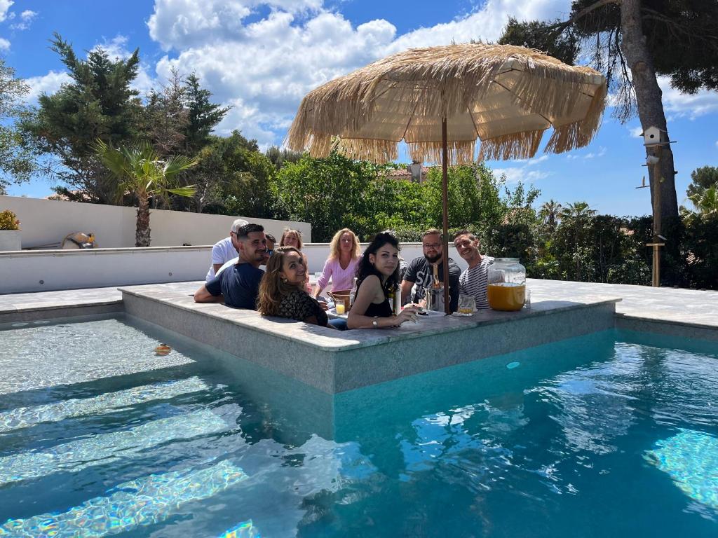 een groep mensen die aan een bar in een zwembad zitten bij Starblue VILLA 172m2 - Mer et spa in Carry-le-Rouet