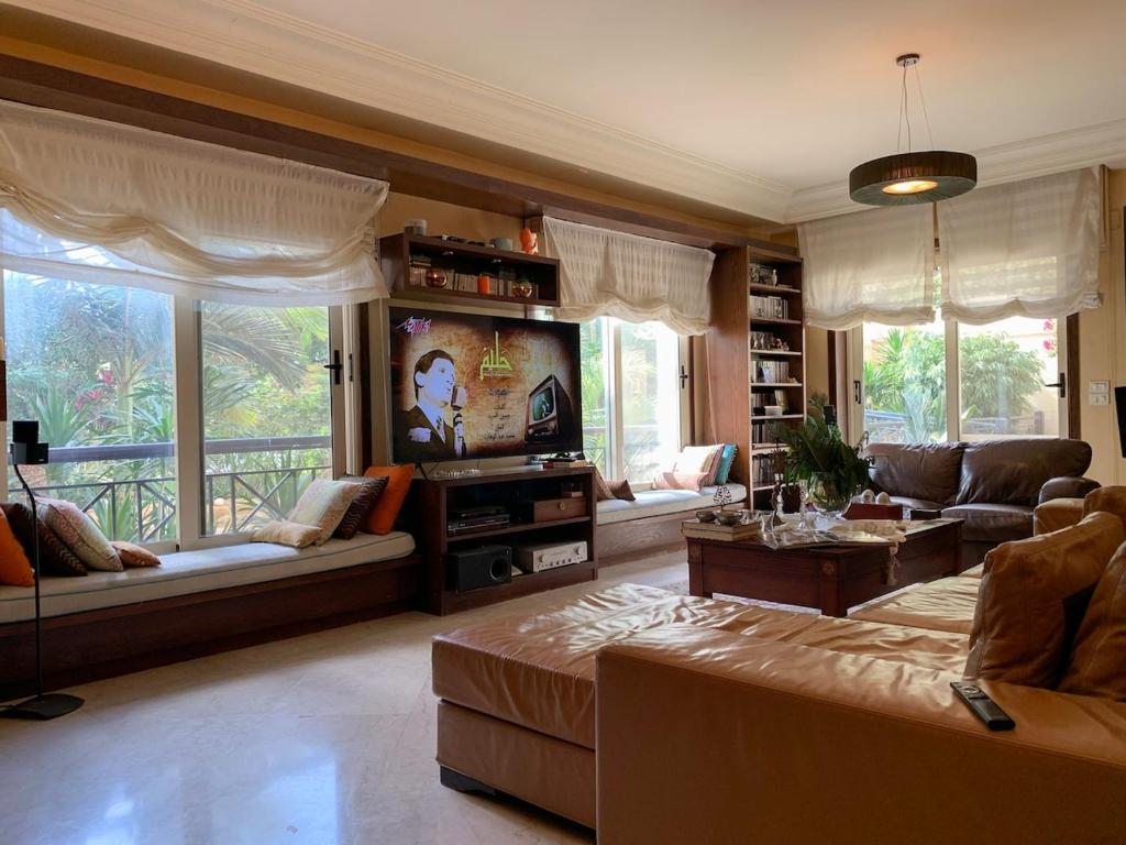 a living room with a couch and a tv at Luxury villa with swimming pool and garden in Sheikh Zayed