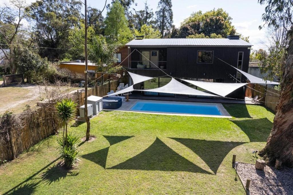 a backyard with a swimming pool and a house at Beach house with heated pool and jacuzzi in Villa Argentina
