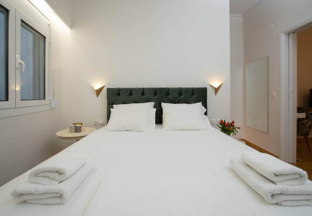 sypialnia z dużym białym łóżkiem i 2 ręcznikami w obiekcie O&O Group Ruby's Urban Residence Koukaki w Atenach