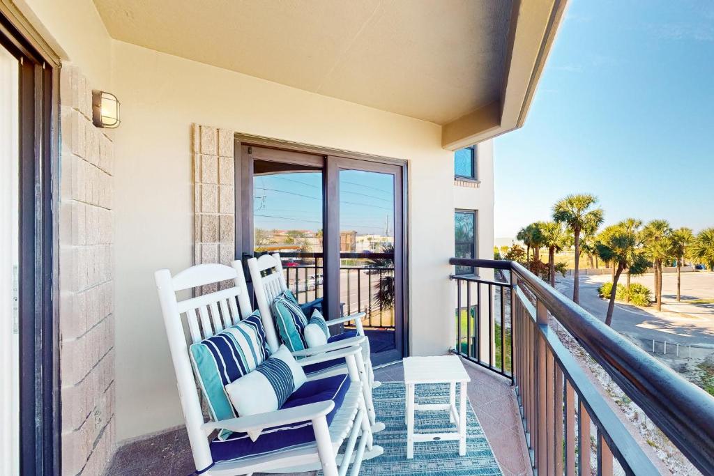 a balcony with two rocking chairs and a view of the ocean at Gulf Strand Resort 308 in St. Pete Beach