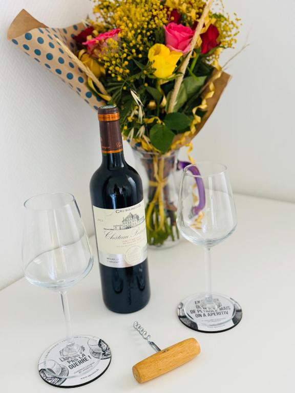 - une bouteille de vin à côté de deux verres et d'un vase de fleurs dans l'établissement DAMA Lodge, à La Ferté-Bernard