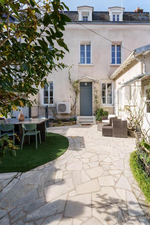 un patio avec une table et des chaises devant une maison dans l'établissement Maison clim jardin Tours centre 8 personnes 4 chambres, à Tours