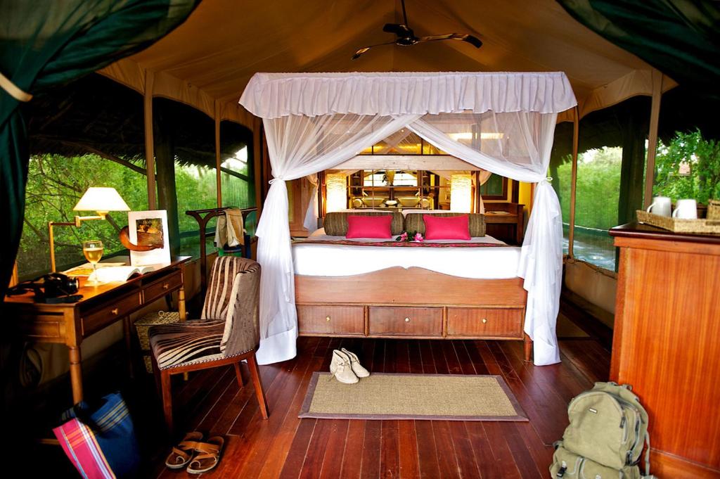 Samburu Intrepids Tented Camp في Archers Post: غرفة نوم مع سرير ومكتب وسرير sidx sidx