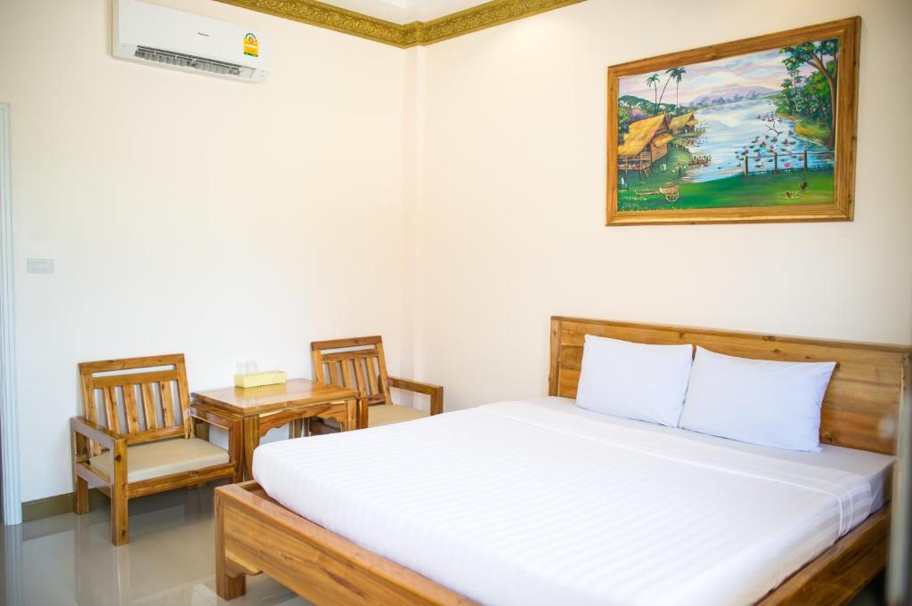 a bedroom with a bed with two chairs and a painting at Pailin Resort in Trat