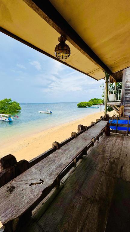 a wooden bench sitting on top of a beach at Fisherman Shack in Nusa Lembongan
