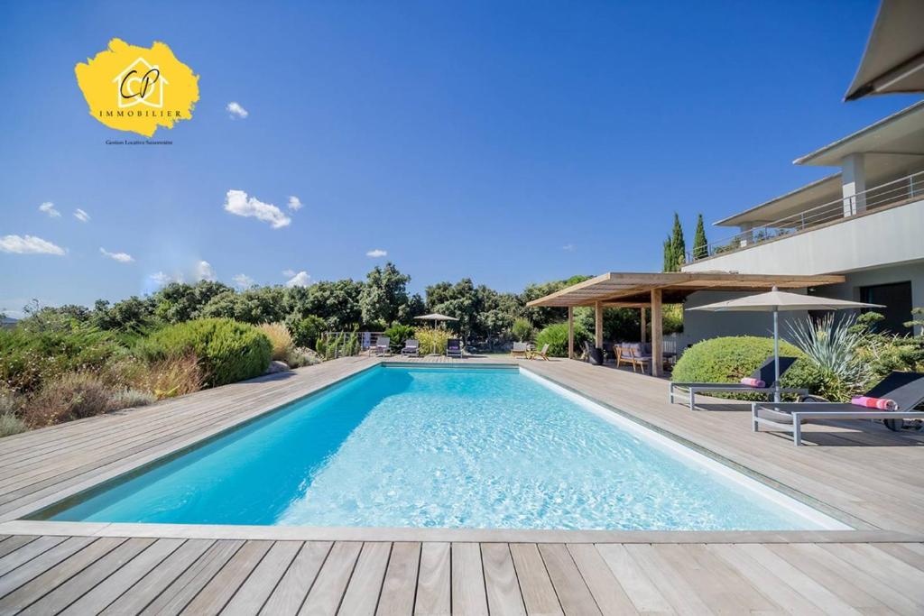 a swimming pool on a wooden deck next to a building at Villa d’exception 4 chambres, piscine, vue mer in Porto-Vecchio