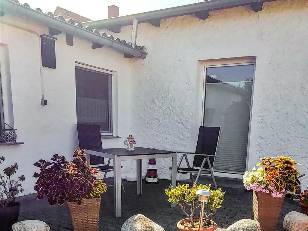 Un patio con mesa y sillas y plantas. en Ferienbungalow Kahmann, en Ribnitz-Damgarten