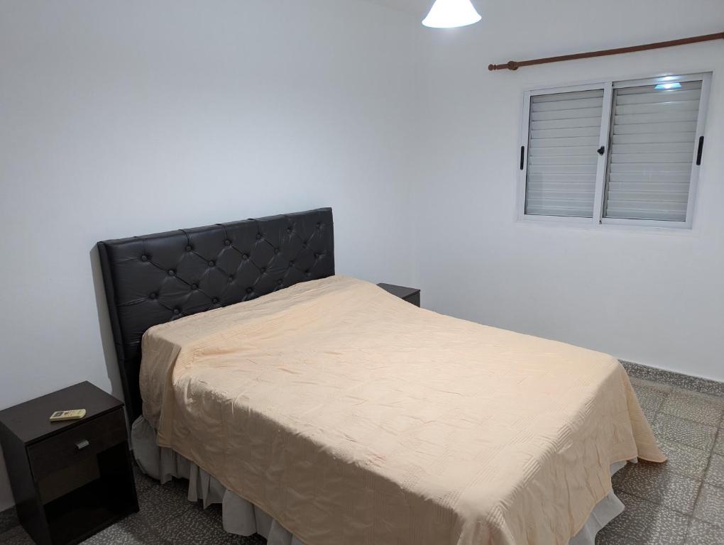 a bedroom with a bed with a black headboard and a window at Departamento Achalay in Chilecito