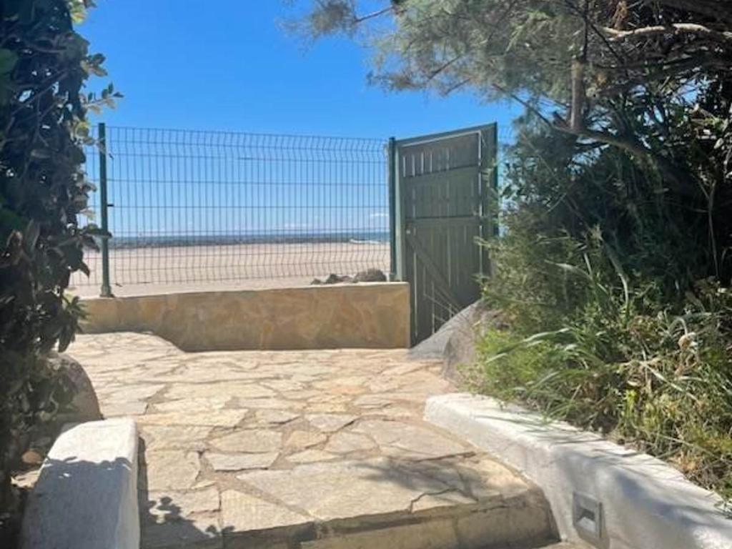 un portail avec une passerelle en pierre menant à la plage dans l'établissement Villa lumineuse pieds dans l'eau, accès plage direct, clim, jardin, Free WIFI, park, idéale famille! - FR-1-423-295, au Grau-dʼAgde