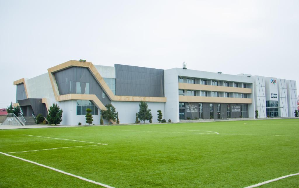 a building with a soccer field in front of it at Arena Hotel Beylagan in Beylǝqan