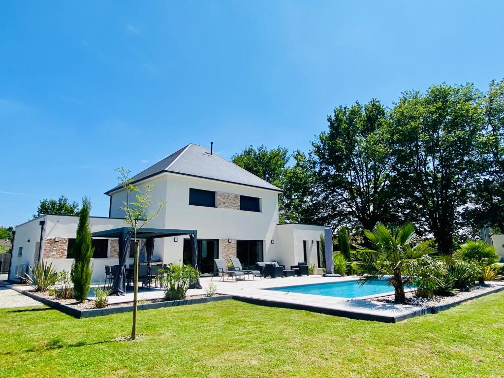 une maison blanche avec une piscine dans la cour dans l'établissement Villa 10 min du circuit des 24h du Mans, à Saint-Gervais en-Belin