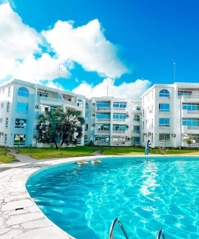 a swimming pool in front of a building at Modern Couzy Suites in Malindi
