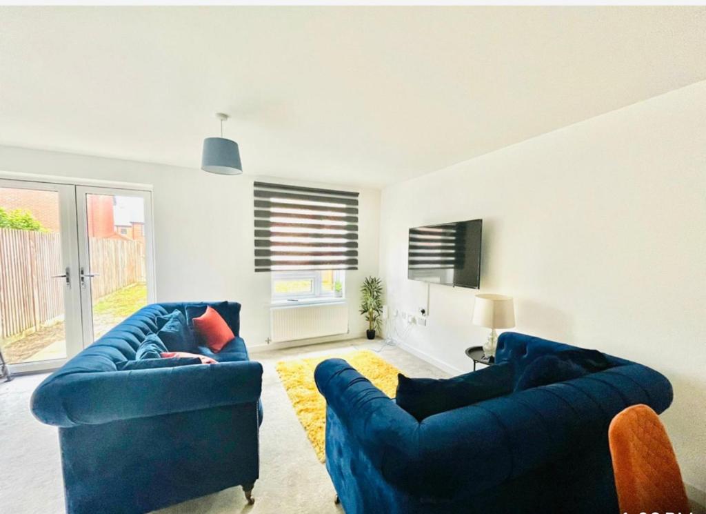 a living room with two blue couches and a tv at Honeybee Haven Retreat - 3 Bed House in Ashford