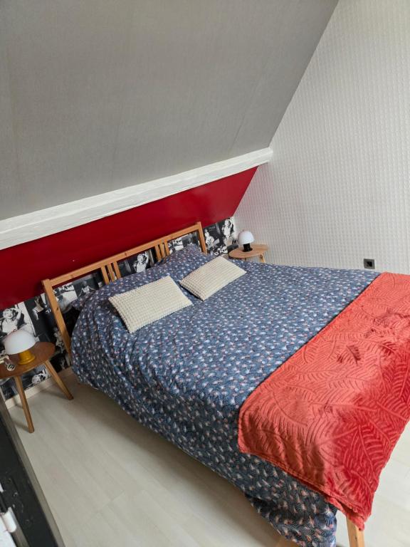 a bedroom with a bed with a red and blue comforter at Maison près de la mer , les plages du débarquement in Courseulles-sur-Mer