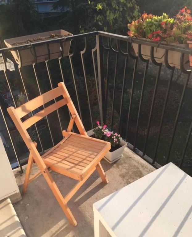 une chaise en bois assise sur une terrasse fleurie dans l'établissement Cosy F1 Parking privé, à Saint-Maur-des-Fossés