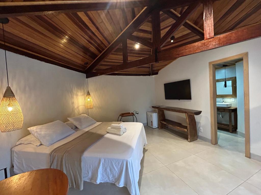 沙帕达-杜斯吉马朗伊斯Pousada Vila Margarida的一间卧室，配有一张床、一台电视和一张桌子