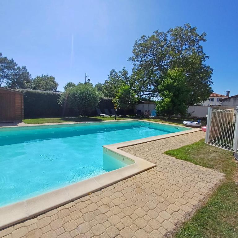 une piscine avec de l'eau bleue dans une cour dans l'établissement Le Fief des Roses, aux Mathes