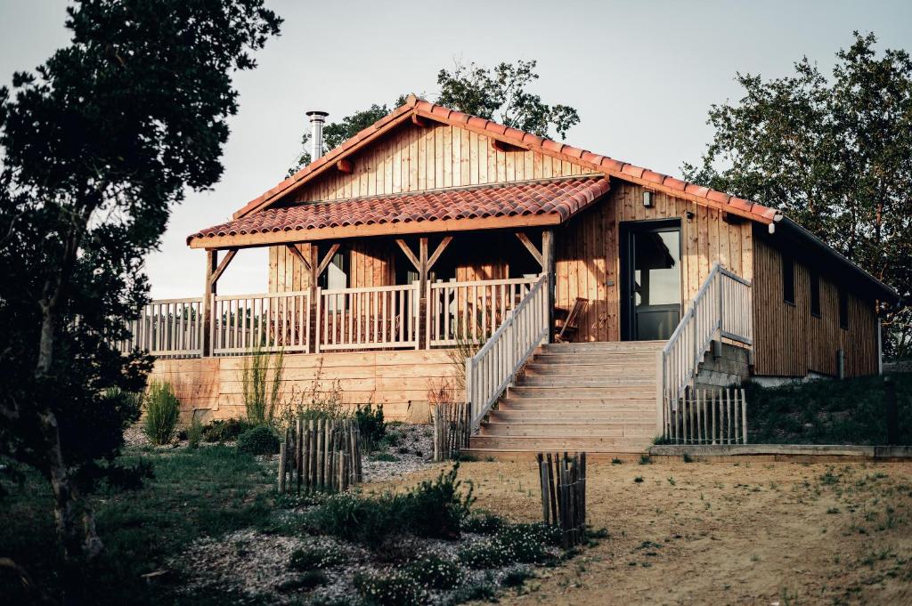 une grande maison en bois avec des escaliers et une terrasse couverte dans l'établissement Maison des Dunes, à Saint-Julien-en-Born