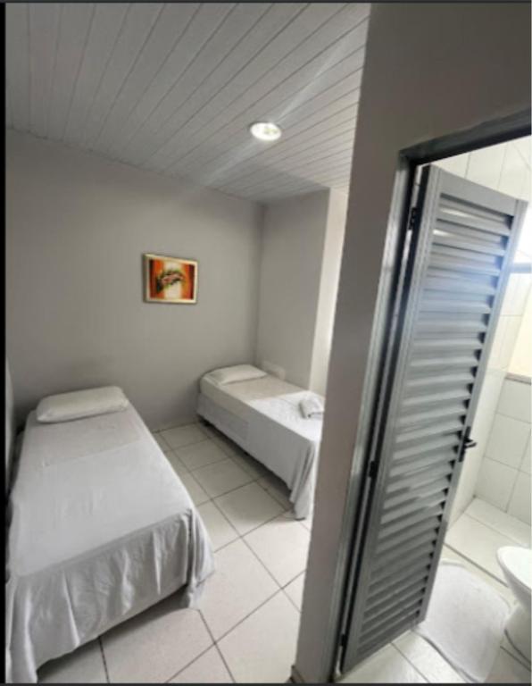 a small room with two beds and a shower at Shopping 44 Hotel in Goiânia