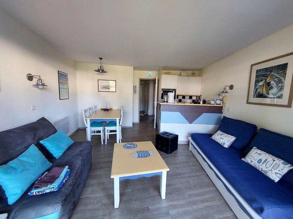 a living room with a blue couch and a table at A 03 Pool apartment with sea view in Fouesnant