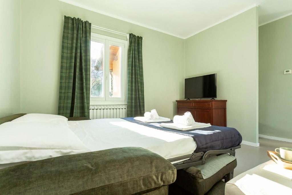 une chambre avec un grand lit et une télévision dans l'établissement Villa Peroni Honeymoon cottage - with swimming pool, à Argegno