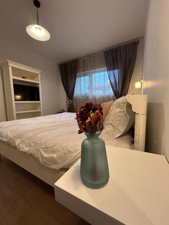 a bedroom with a bed with a vase on a table at Serelor Cozy Flat in Dumbrăviţa