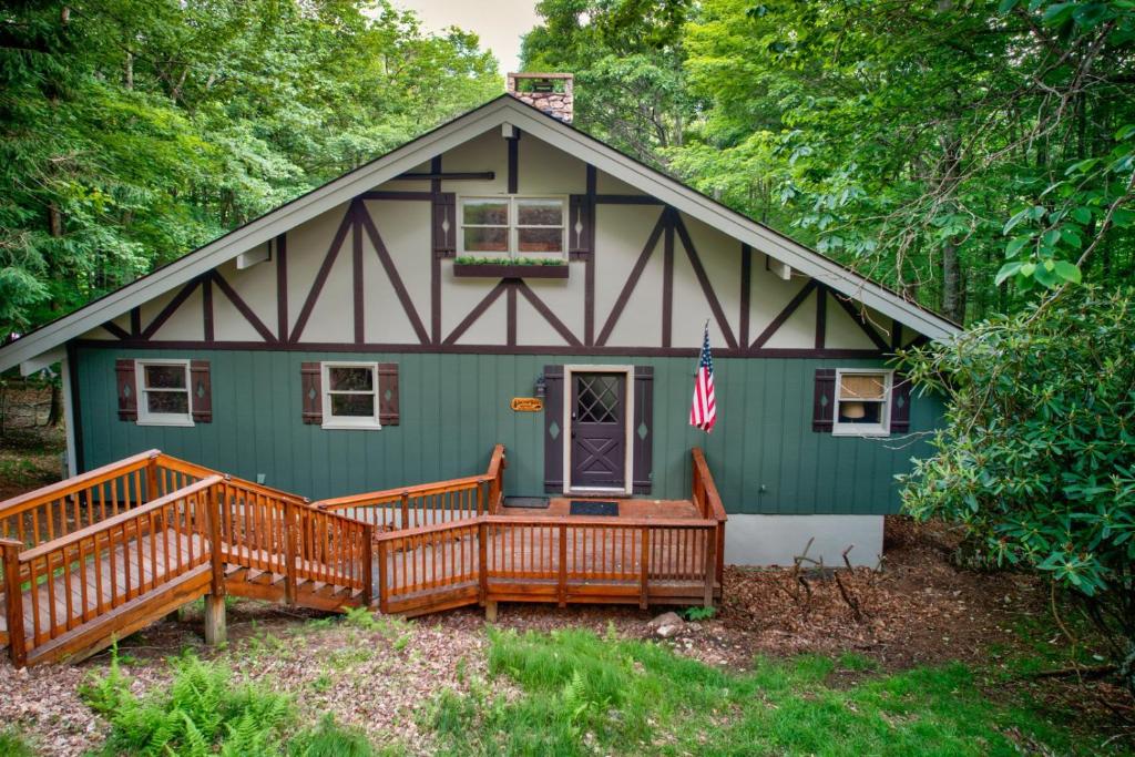 a green house with a porch and a flag on it at Southern Buffalo in Beech Mountain