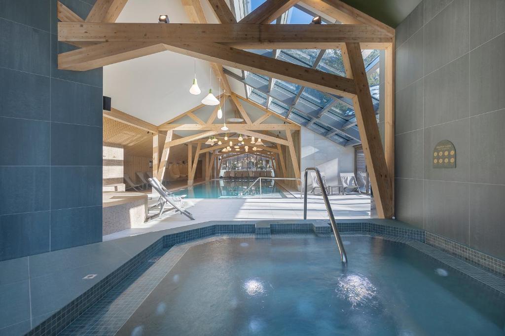 a swimming pool in a house with a wooden ceiling at Lykke Hôtel & Spa Chamonix - ex Mercure in Chamonix-Mont-Blanc