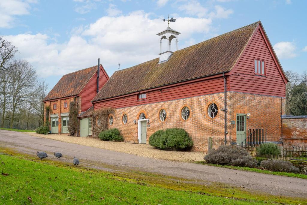 a red barn with a cross on top of it at Belchamp Hall Hayloft and Stables in Belchamp Otten