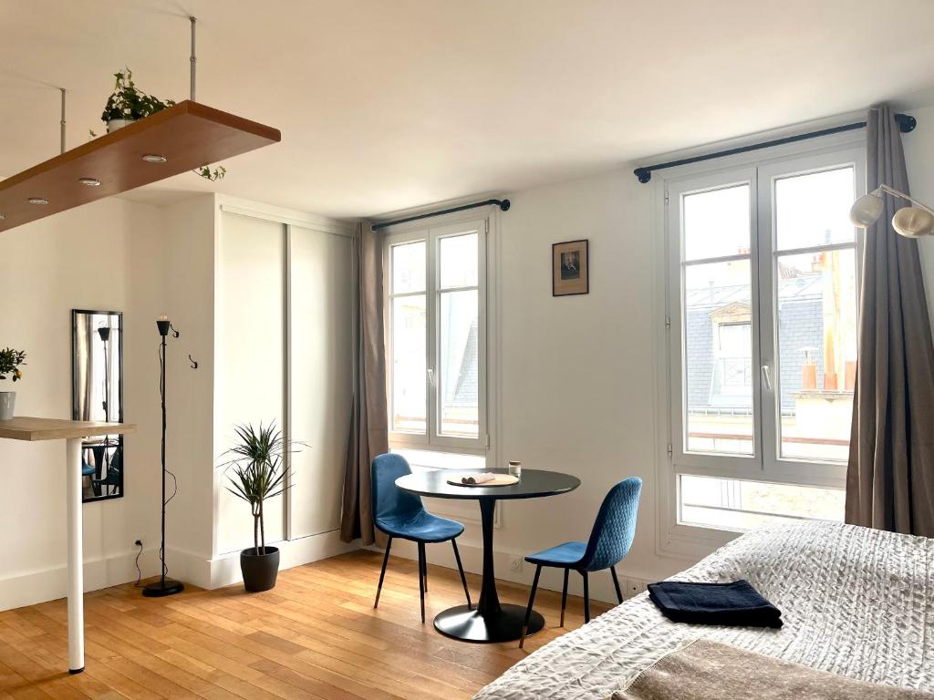 une chambre avec un lit, une table et des chaises dans l'établissement Eiffel Tower - Cosy Studio, à Paris