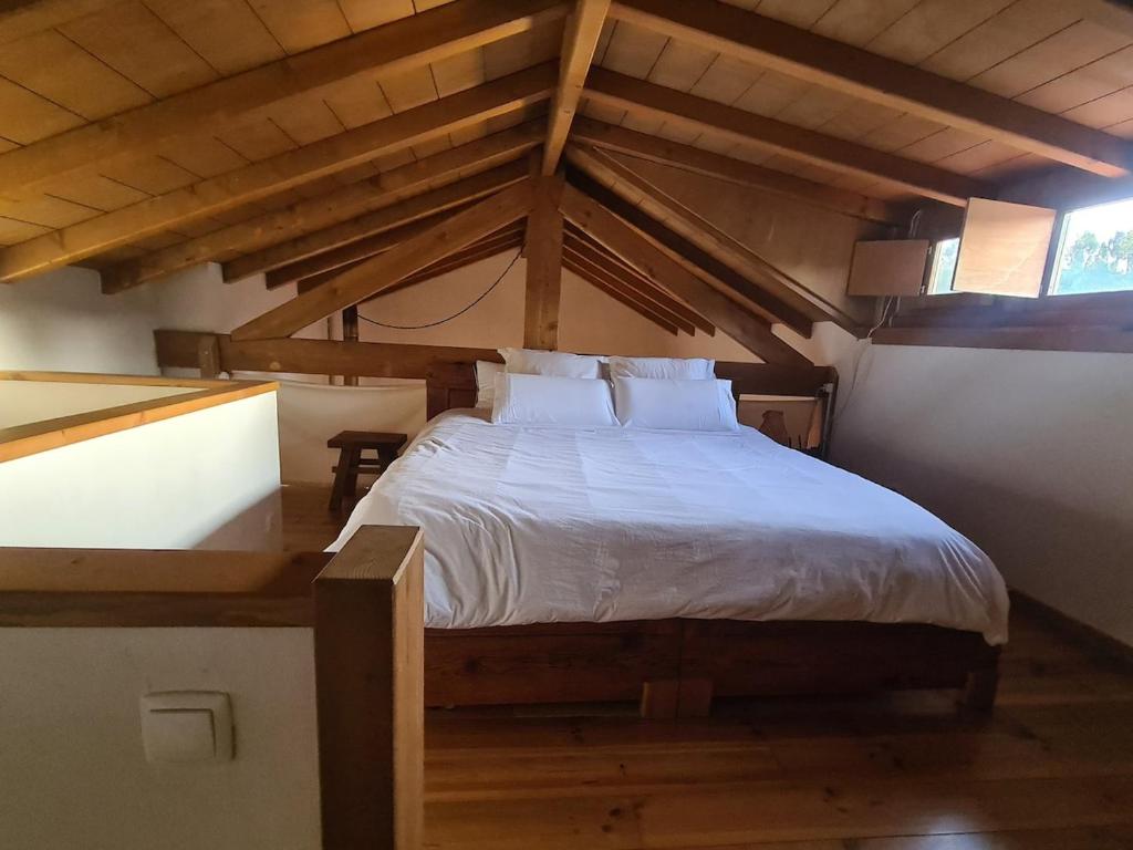 a bedroom with a large bed in an attic at Quinta dos Milagres Casa dos Bigodes in Friumes