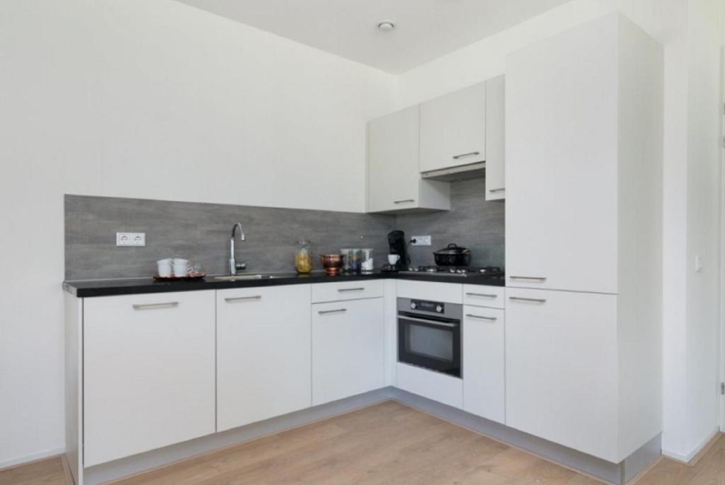 une cuisine blanche avec des armoires blanches et un évier dans l'établissement 2 chambres WC séparés, à Saint-Germain-du-Crioult