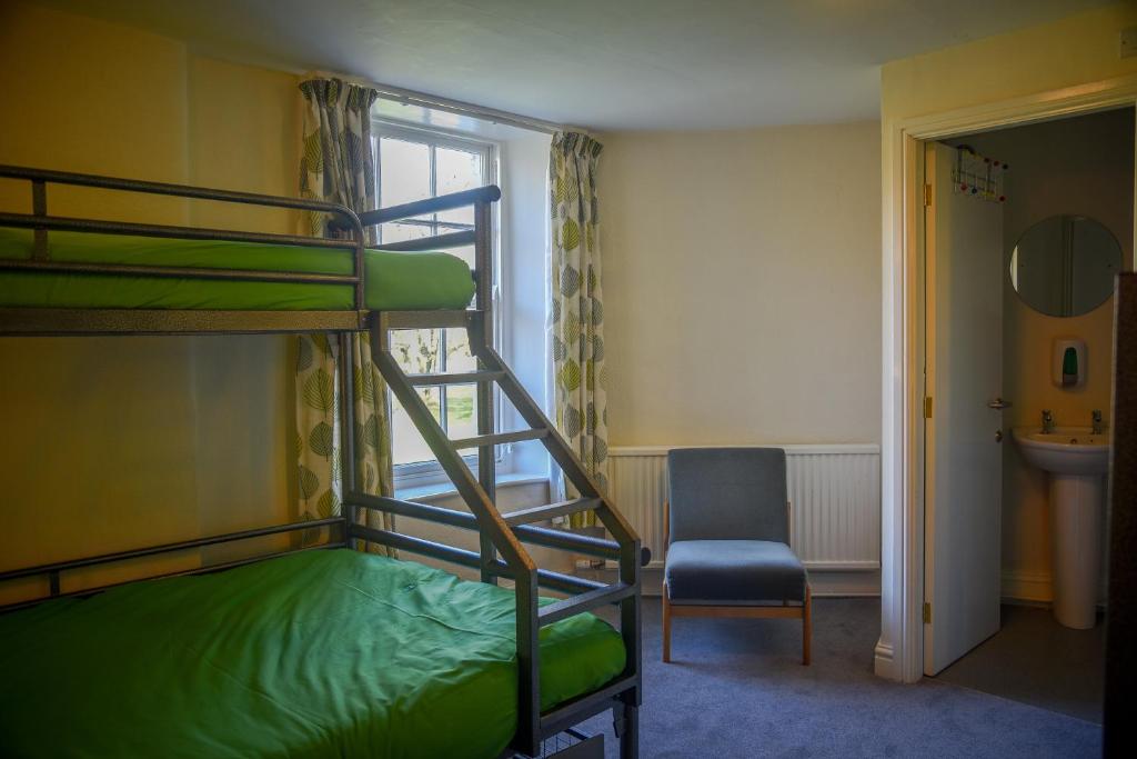 Ingleton Hostel في إنغيلتون: غرفة نوم بسريرين بطابقين وكرسي