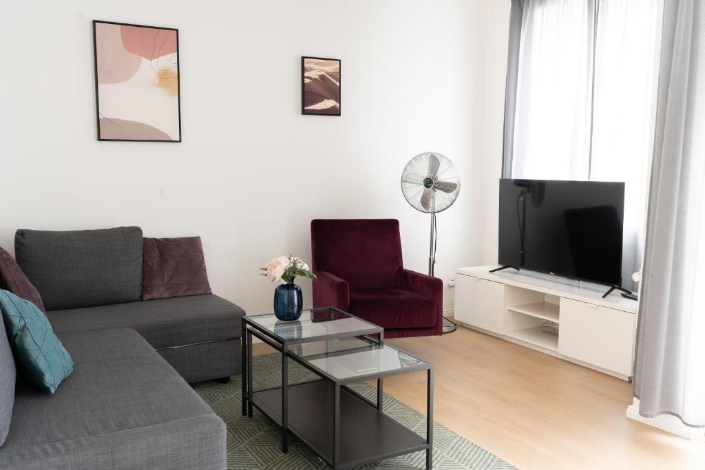 Una sala de estar con un sofá y un televisor. en URBAN FLATS Berlin, en Berlín