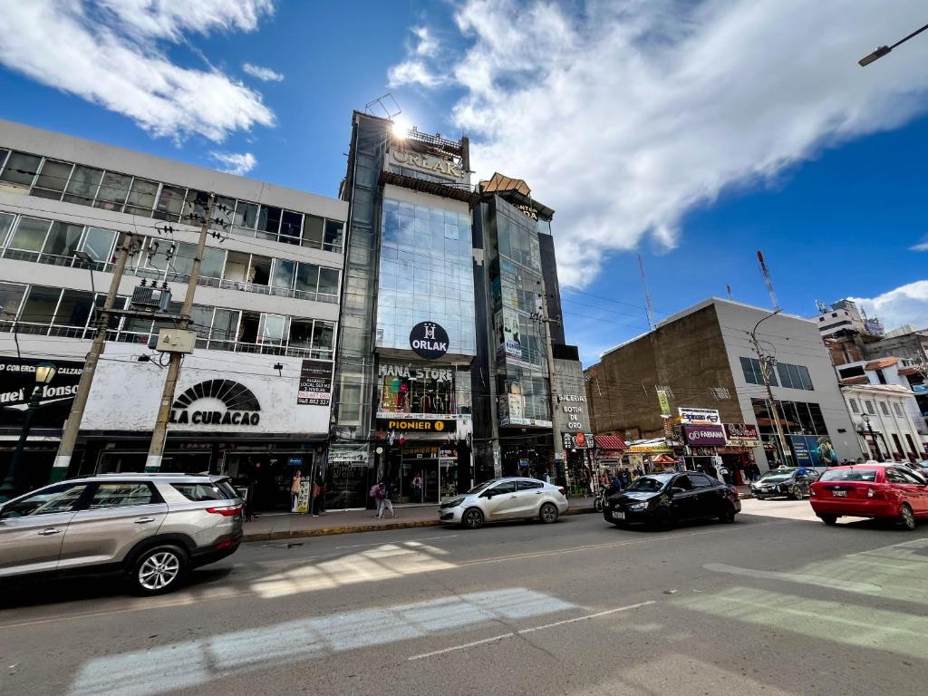 a busy city street with cars parked in front of buildings at Hotel Orlak in Huancayo