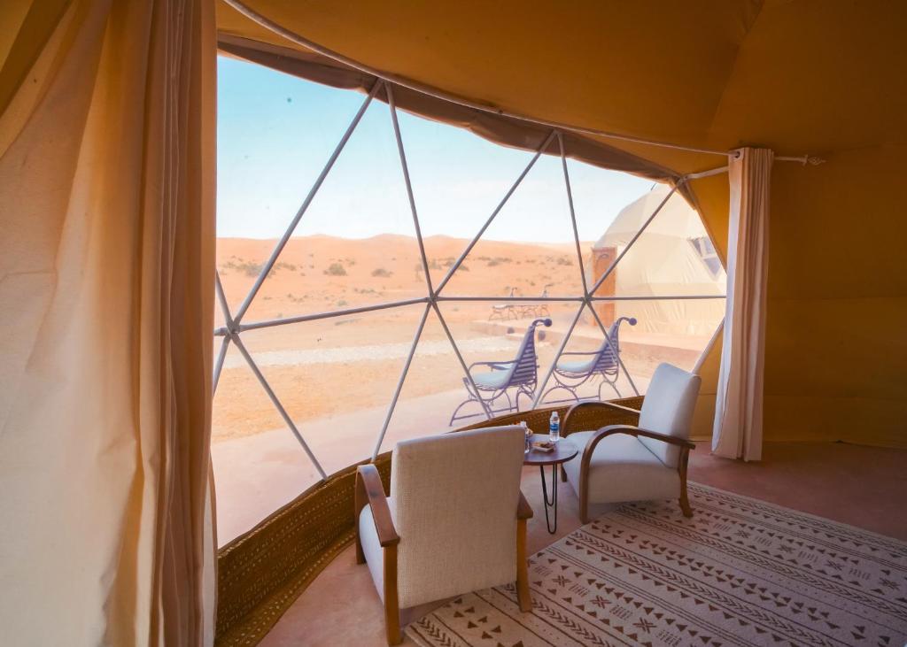 a room with a view of the desert from a tent at Antares Desert Camp in Merzouga