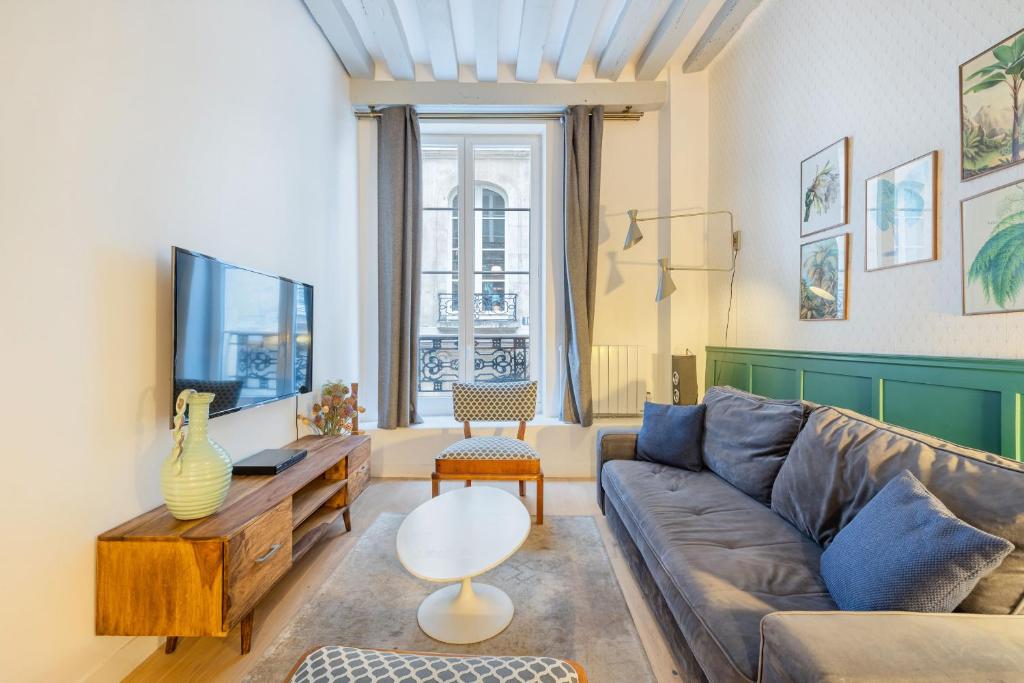 un salon avec un canapé et une télévision dans l'établissement Strata, à Paris